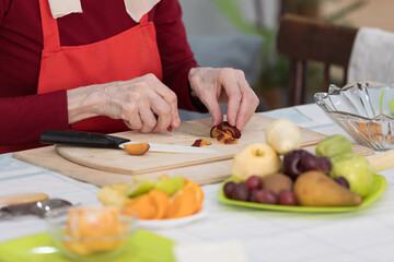 Elderly woman preparing fruit salad at home in the living room