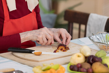 Elderly woman preparing fruit salad at home in the living room