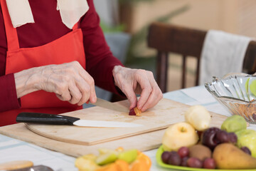 Elderly woman preparing fruit salad at home in the living room