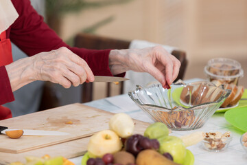 Elderly woman preparing fruit salad at home in the living room