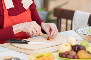 Elderly woman preparing fruit salad at home in the living room