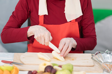 Elderly woman preparing fruit salad at home in the living room