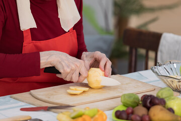 Elderly woman preparing fruit salad at home in the living room
