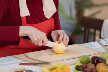 Elderly woman preparing fruit salad at home in the living room