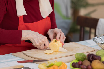 Elderly woman preparing fruit salad at home in the living room
