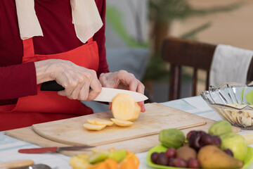 Elderly woman preparing fruit salad at home in the living room