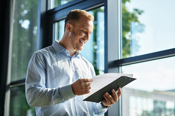 Fototapeta premium Young businessman focused on work while reviewing documents in a bright office environment