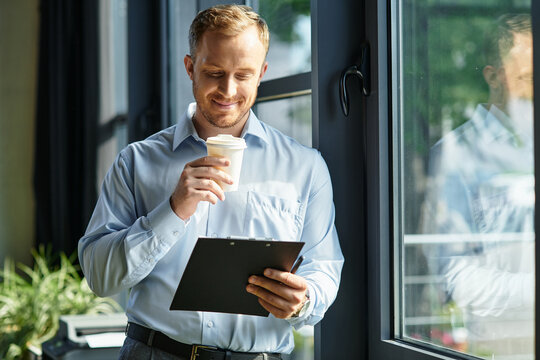 Young businessman reviews notes while enjoying coffee in modern office setting