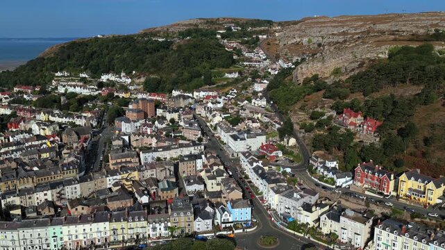 Aerial video of Llandudno, Wales, showing a mix of Victorian-style houses, modern buildings, and winding streets nestled against the Great Orme hillside