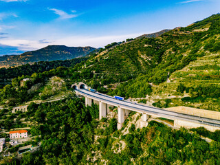 Aerial view of highway road with tunnel in mountains. Traffic on the road, cargo trucks logistic...