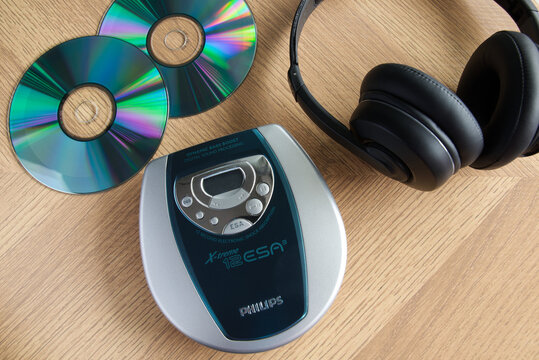 Philips Discman next to headphones and music CDs on a wooden background