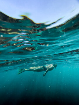 Underwater of female snorkelling in ocean afloat at surface looking down