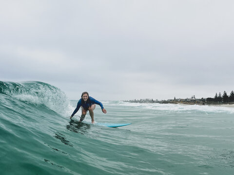 Woman surfing wave on fiberglass mid length board on overcast day
