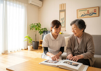 Fototapeta premium Caregiver and senior woman looking at photo album at home