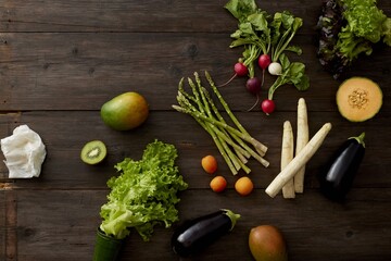 Fresh fruits and vegetables arranged on dark rustic wooden tabletop