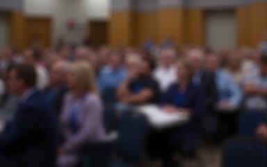 Conference Audience Blur: A blurred background of an audience at a conference or seminar, with rows of seats and people listening attentively. High quality