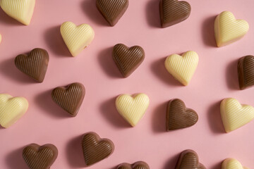 Heart-shaped chocolate pieces over pink background, abstract food love background
