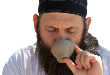 A bearded man in a bandana is drinking tea on the background of nature.