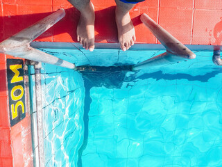 Bare feet dangling over the edge of the pool. This serene setting captures the essence of summer...