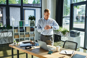 Handsome young businessman checking time while working in a modern office environment