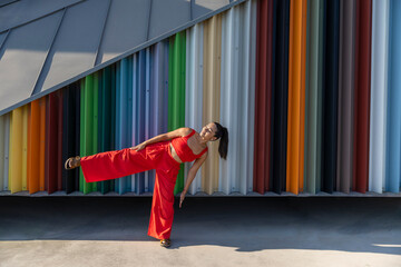 Fashionable woman posing in red outfit against colorful metallic wall