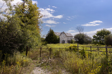 Neglected deserted old house sits amongst overgrown weeds in rural southern Ontario Canada