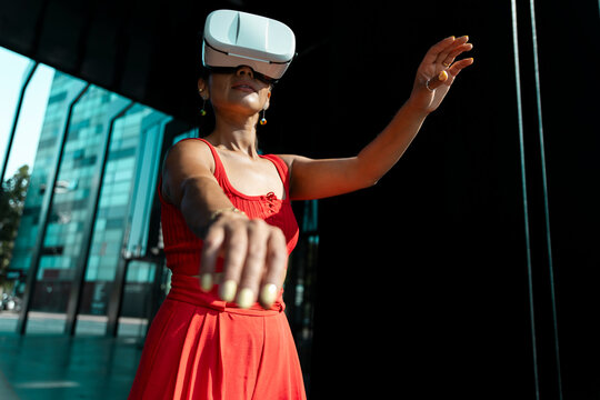 Woman in red outfit using VR headset outdoors in urban setting
