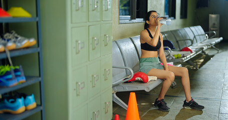 Indian relax young adult woman lady sitting chair hold bottle drink water indoor room Asian relax...