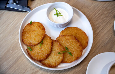 draniki on a white plate with sour cream
