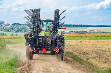 Tractor with cultivator driving along rural dirt road. Agricultural machinery, agriculture concept.