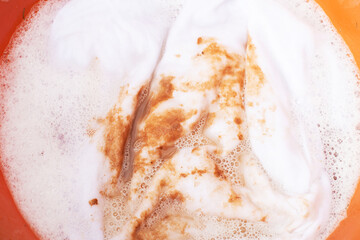 Soaking stained white clothes in detergent for laundry and hygiene