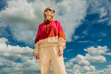 Trendy person in retro 1990s sportswear posing outdoors under blue sky