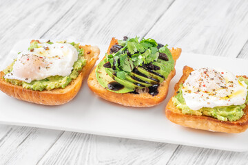 Ciabatta sandwiches with poached egg, avocado mash, sundried tomato and herbs