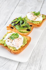 Ciabatta sandwiches with poached egg, avocado mash, sundried tomato and herbs