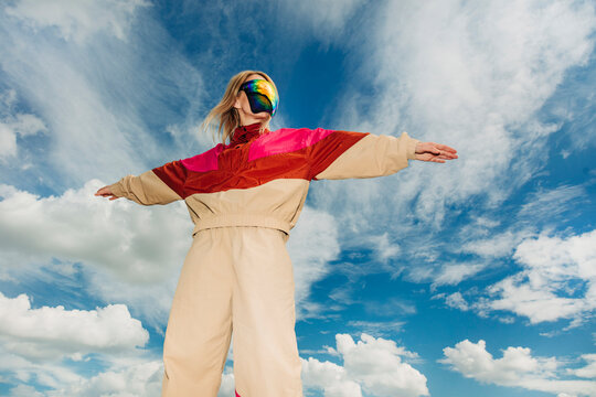 Person in retro 1990s sportswear posing outdoors under blue sky