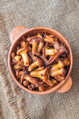 Rustic bowl filled with golden fried chanterelle mushrooms on table