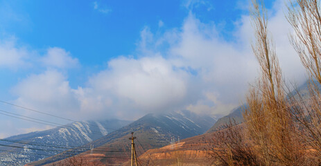 Landscape is with mountain gorges in background, peaks are hidden by low clouds, the slopes are...