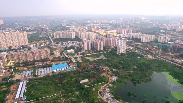 Aerial drone shot showing the outskirts of gurgaon with water logging ponds and marshes created by the monsoon surrounded by temporary slum residences and construction sites