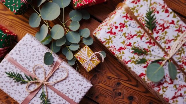 Overhead View of Wrapped Christmas Presents Decorated with Ribbon String Eucalyptus and Holly Leaves