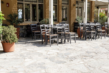 Stock photo of an empty outdoor cafe patio with tables and chairs on a sunny day. Perfect for restaurant, cafe, or travel websites.