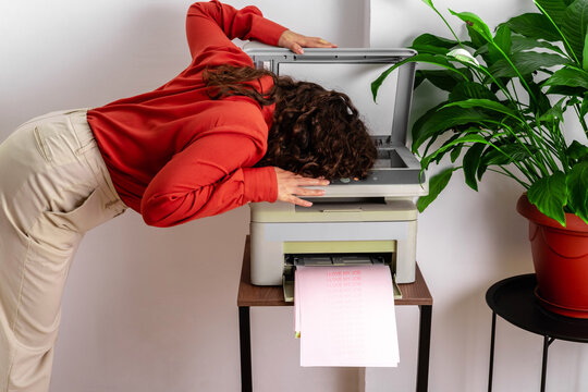 Office worker with head on photocopier experiencing burnout stress