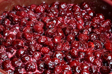 Delicious cherry jam in a saucepan on a wooden table, closeup, top view. Summer preparation and preservation of berries for the winter, home cooking