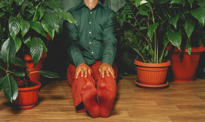Man blending with indoor houseplants in creative humorous portrait