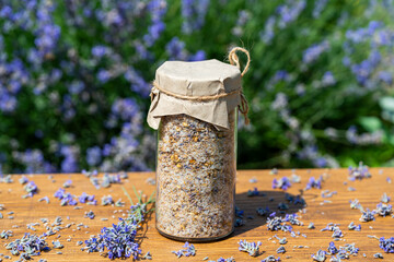 Sea himalayan salt with dry lavender and chamomile flowers in a glass jar against lavender flowers...