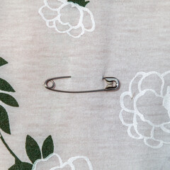Silver pin is on a white background with a floral pattern