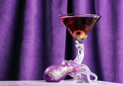 Halloween cocktail with eyeball garnish and octopus glass in bright purple