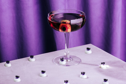 Halloween cocktail with eyeball decoration on purple background
