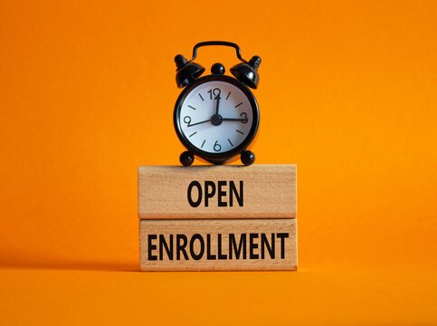 Open Enrollment symbol. Wooden blocks with words Open Enrollment. Beautiful orange background with alarm clock. Business and Open Enrollment concept. Copy space.