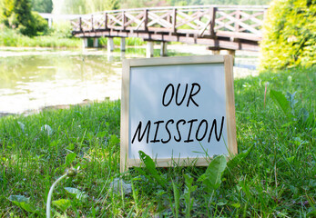 Our Mission symbol. Concept word Our Mission on white chalk blackboard. Beautiful meadow background with bridge. Business and Our Mission concept. Copy space.