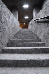 Concrete staircase in dim underground tunnel leading upwards.